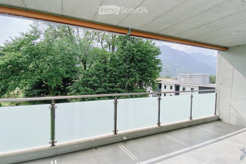 Balcony with modern glass railing, tiled floor, and scenic mountain view.