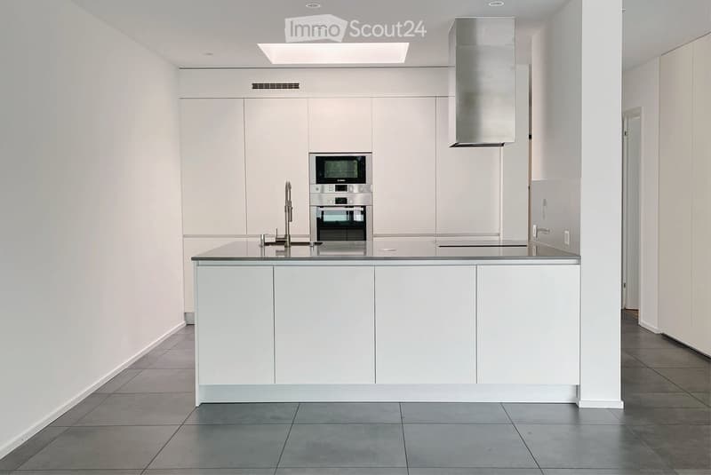 Modern, minimalist kitchen with white cabinets, stainless steel appliances, and a central island with a black countertop.