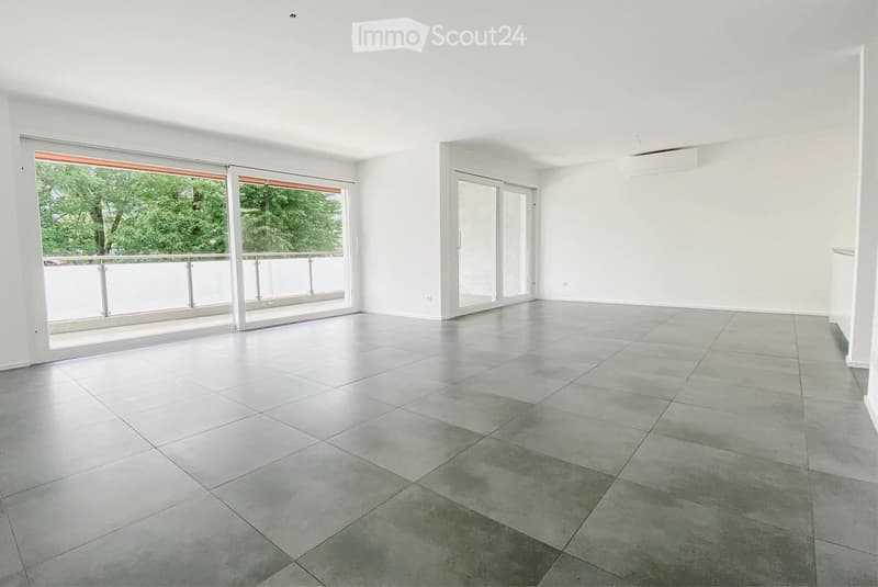 Empty room with large sliding glass doors leading to a balcony, tiled floor, white walls, and bright natural lighting.