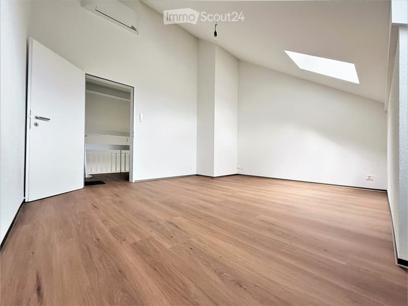 Empty room with wooden flooring, white walls, and a partially open door leading to a closet area.