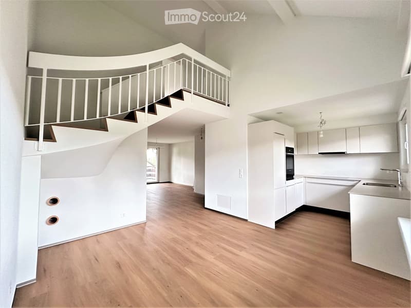 Modern, minimalist kitchen with white cabinets, a central island, and a sleek staircase leading to an upper level.