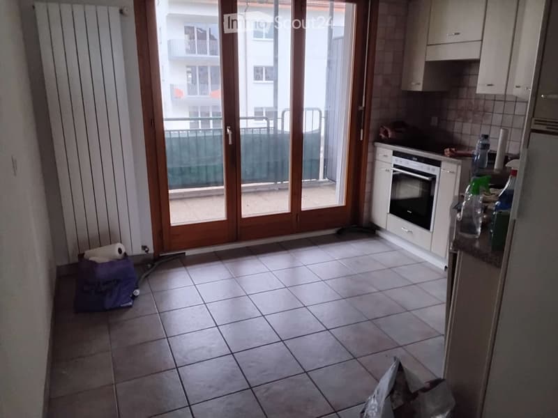 Kitchen with tiled floor, white cabinets, oven, and a sliding glass door leading to a balcony.