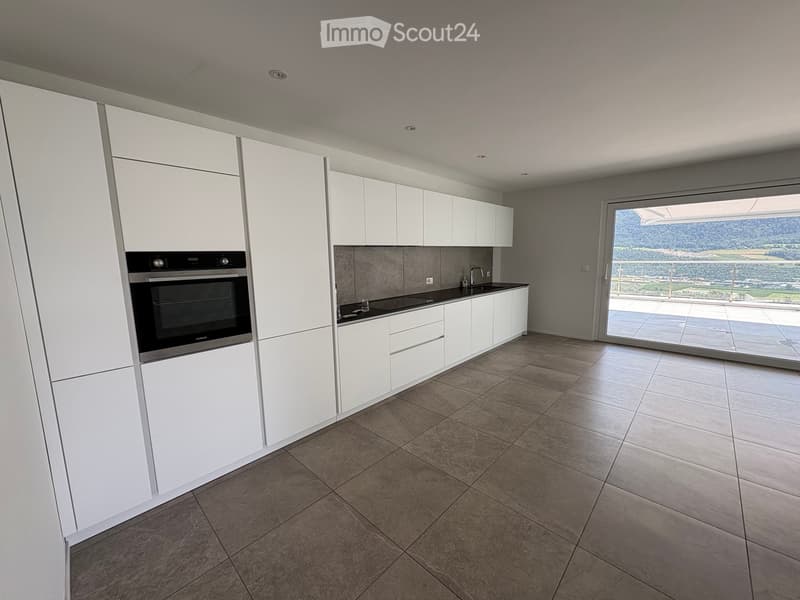 Modern kitchen with white cabinets, stainless steel oven, and a large window offering a scenic view.