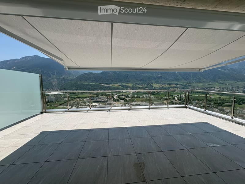 Modern balcony with large retractable roof, glass walls, and expansive mountain view.
