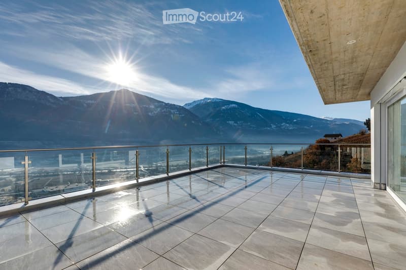 Modern balcony with glass railing, polished tile floor, and panoramic mountain view.