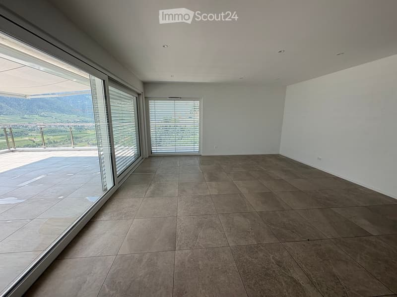 Empty room with large windows and a view of a landscape, featuring tiled flooring and white walls.