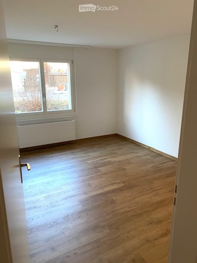 Empty room with wooden flooring, white walls, and a window with a radiator below it. No furniture or equipment present.