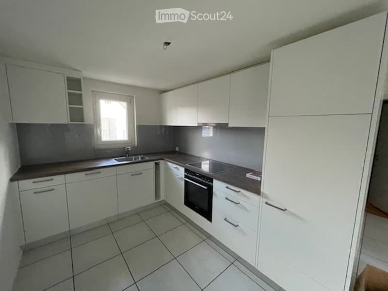 Modern kitchen with white cabinets, tiled floor, and stainless steel appliances including a sink, oven, and dishwasher.