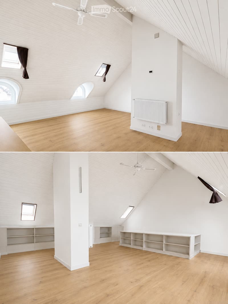 Bright, empty attic room with wooden flooring, white walls, exposed wooden beams, and a ceiling fan. Features large windows with dark curtains, built-in shelving units, and a radiator.