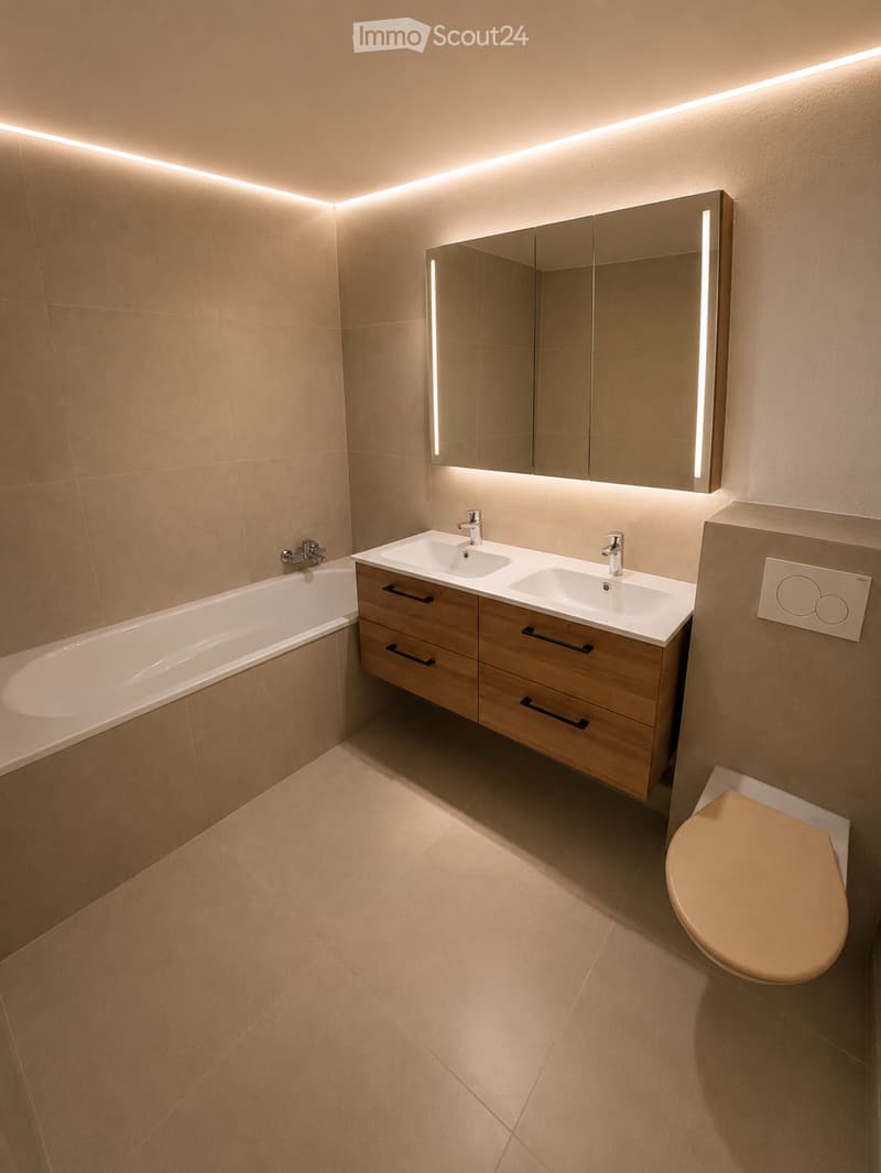 Modern bathroom with beige tiles, a bathtub, a double sink with wooden cabinet, a large mirror with LED lighting, and a toilet.