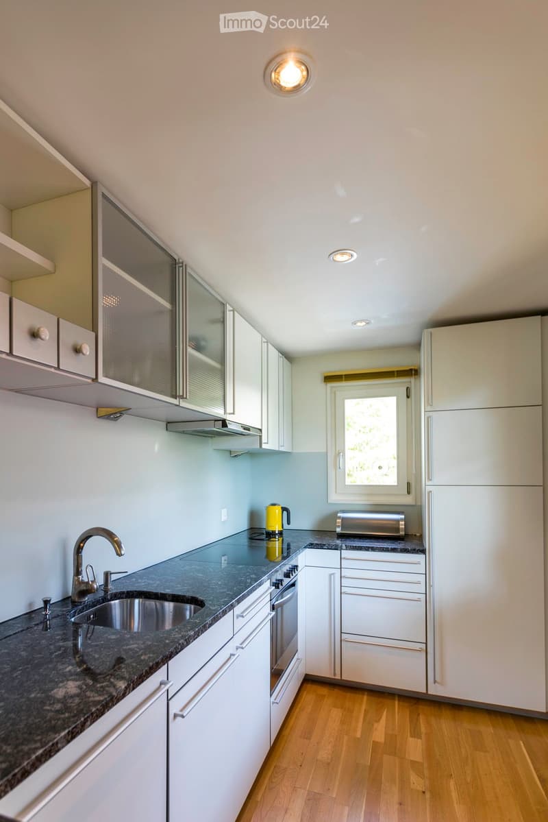 Modern kitchen with white cabinets, granite countertops, stainless steel sink, and appliances including a toaster and kettle.