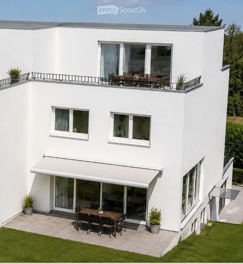 Modern two-story white house with large windows, a covered patio, and a rooftop terrace with outdoor furniture.