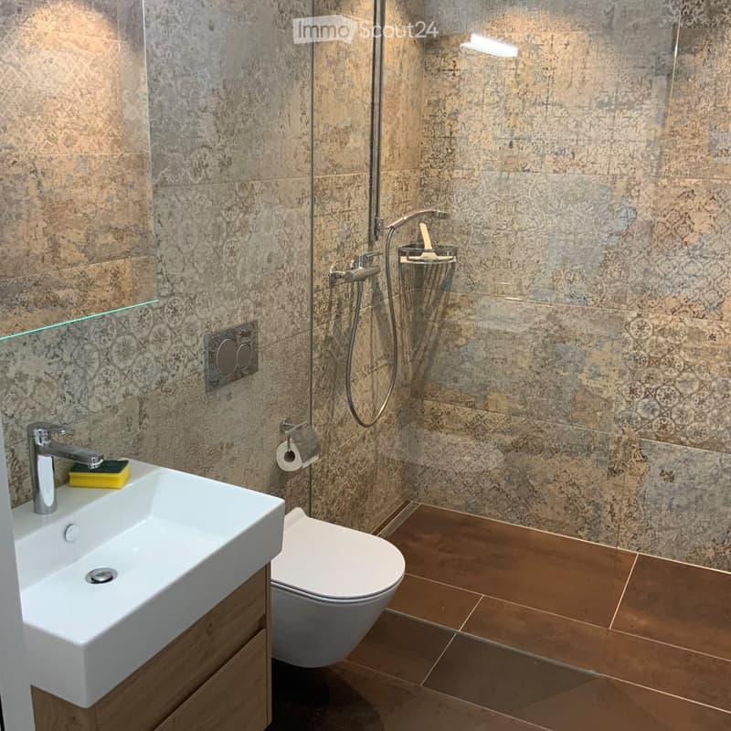white sink, white toilet, shower head, tiled wall