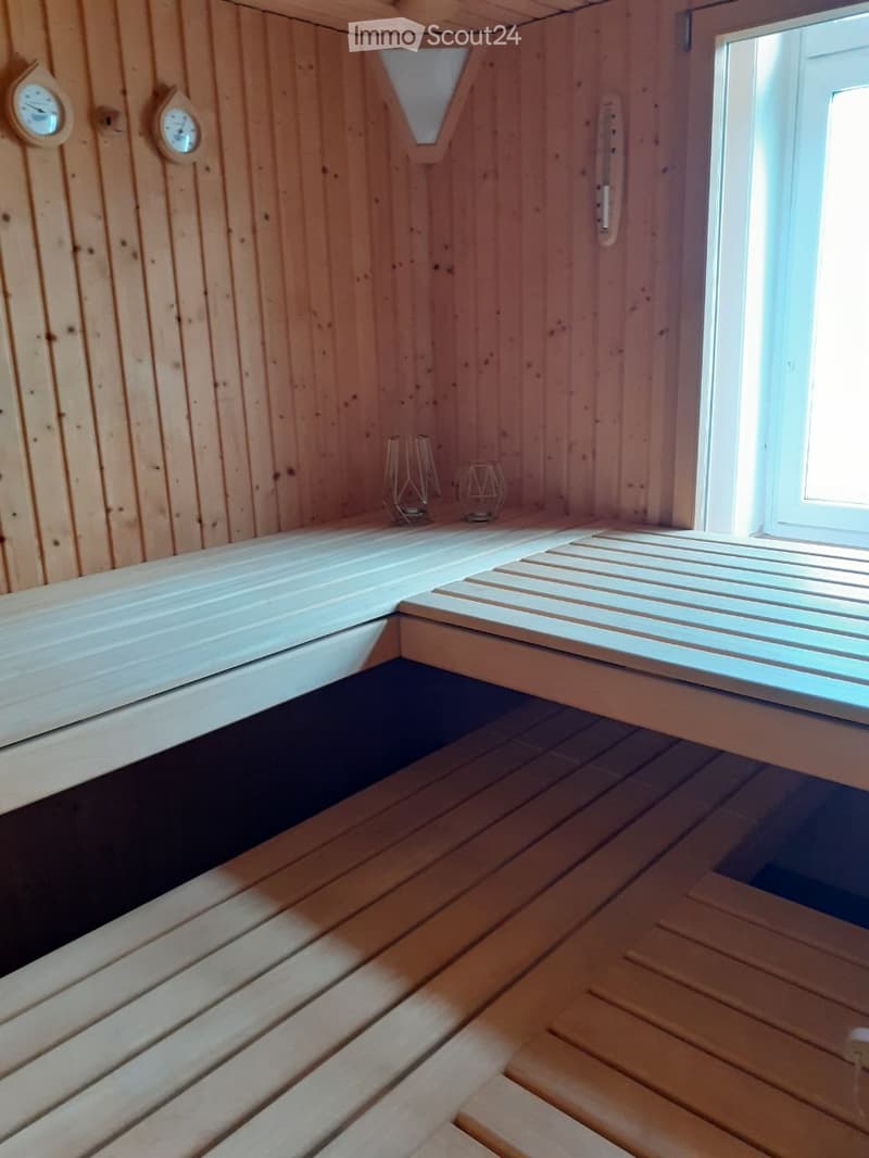 Wooden sauna interior with benches, a window, and two wall-mounted clocks.