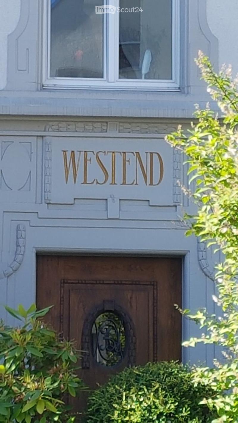 Facade of a building with a wooden door and decorative stonework, featuring the word "WESTEND" above the entrance.