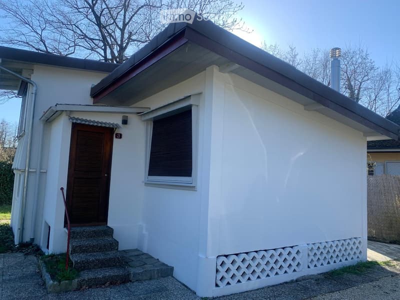 Single-story white house with a flat roof, small porch, and steps leading to the entrance.