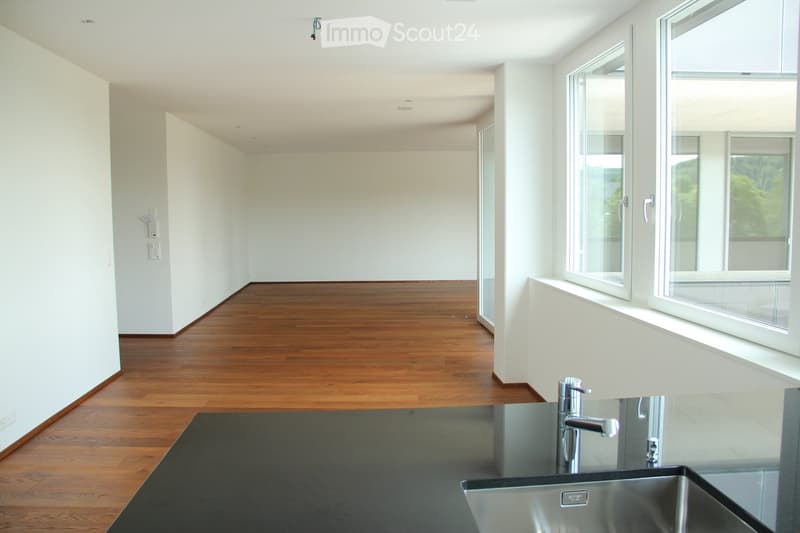 Empty room with white walls, wooden flooring, and large windows allowing natural light. No furniture or equipment present.