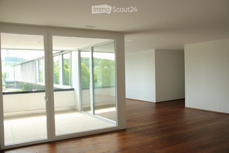 Empty room with wooden flooring, large sliding glass doors leading to a balcony, and white walls.