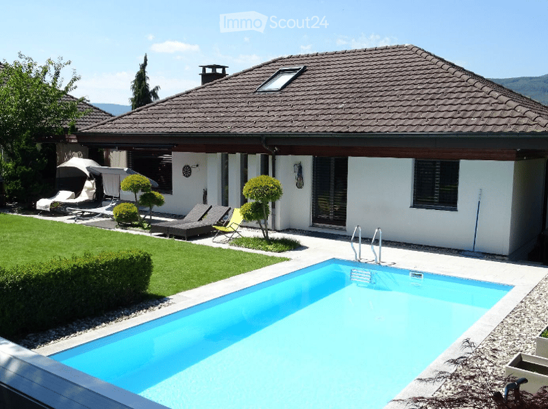 Modern house with brown roof, white walls, swimming pool, garden, lounge chairs, umbrellas