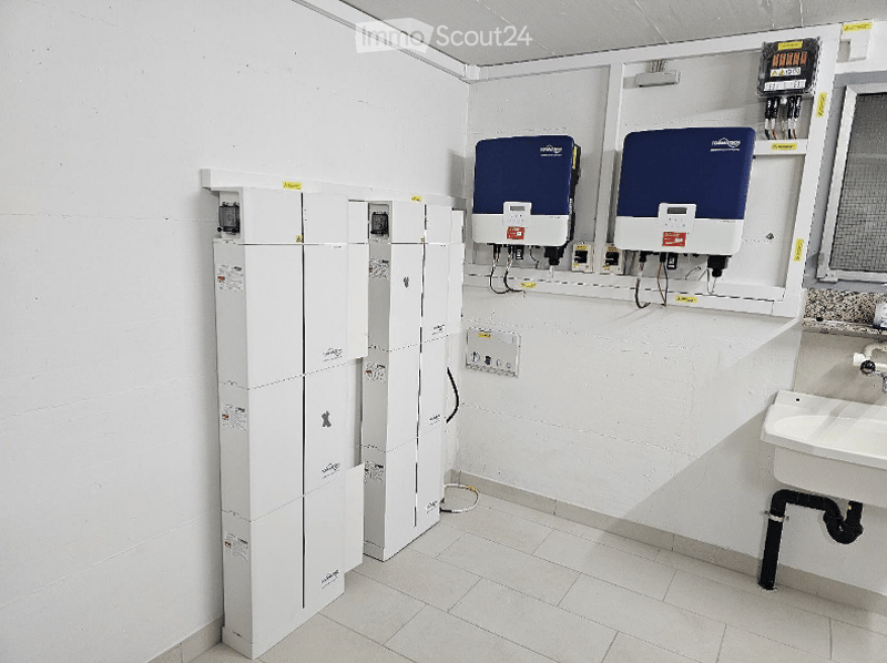 A room with white walls, tiled floor, white cabinets, electrical panels, and a sink.