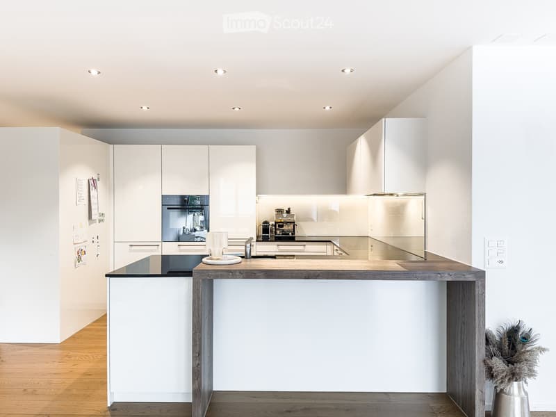 Modern kitchen with white cabinets, a wooden island, and a coffee maker on the counter.