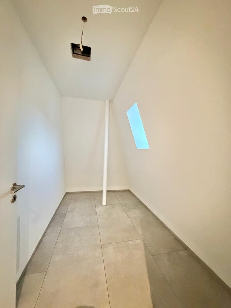 Empty hallway with tiled floor, white walls, a single door on the left, and a small light fixture on the ceiling.