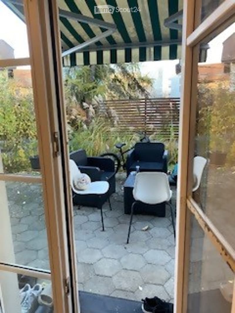 Outdoor patio area with furniture and plants, green striped canopy