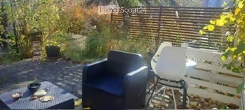Outdoor area with garden, patio chairs, table, wooden fence