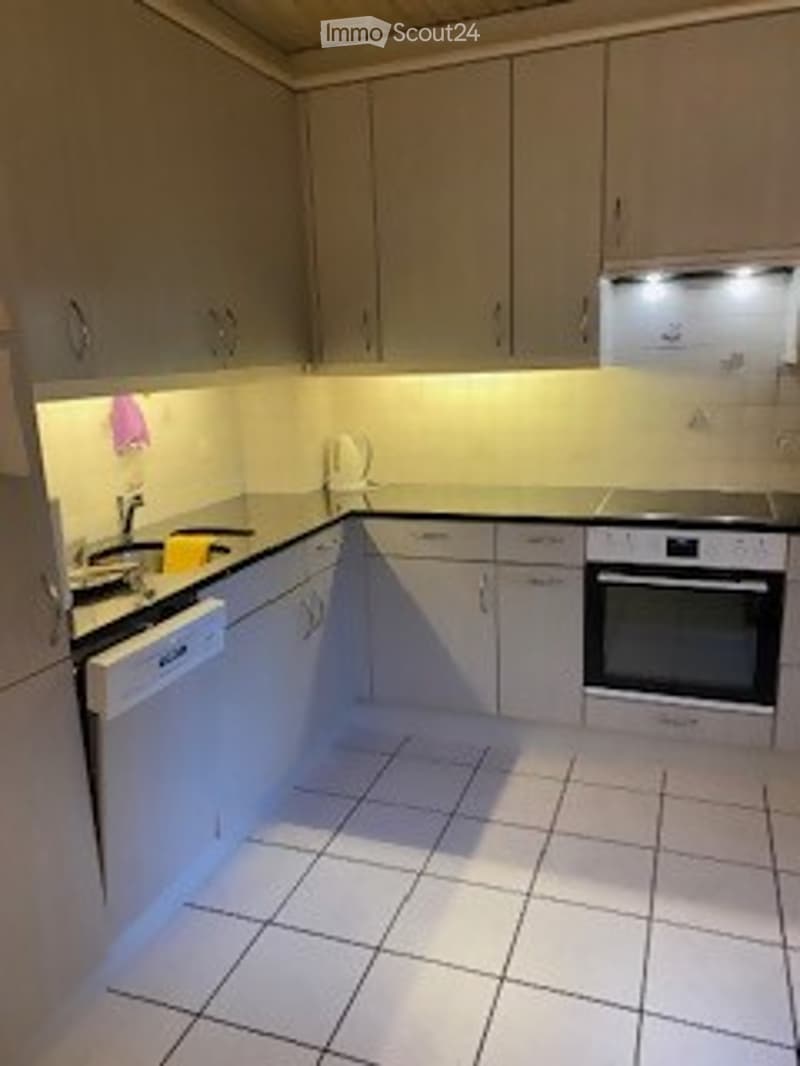 Modern kitchen with white cabinets, tiled floor, and built-in appliances including an oven and dishwasher.