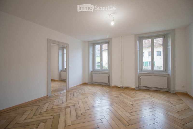 empty room, wooden parquet floor, white walls, two windows, radiators, ceiling light