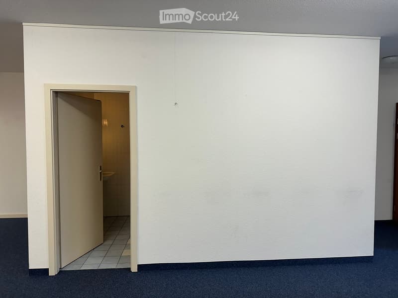 Empty hallway with white walls, carpeted floor, and an open door leading to a tiled bathroom area.