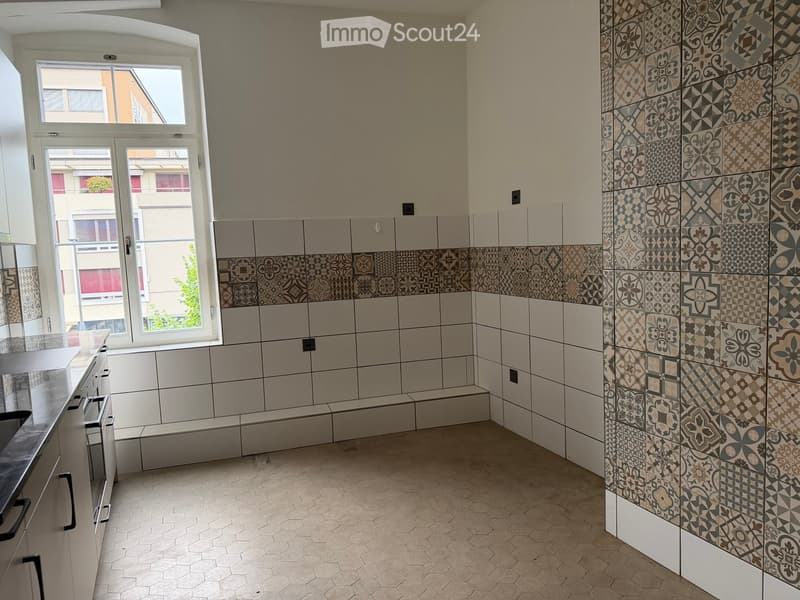 Modern bathroom with white and grey tiles, decorative tile patterns, hexagonal floor tiles, and a large window providing natural light.