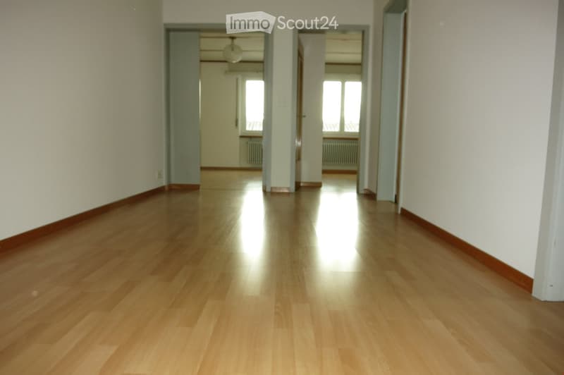 Empty hallway with polished wooden flooring, white walls, and two open doorways leading to other rooms.