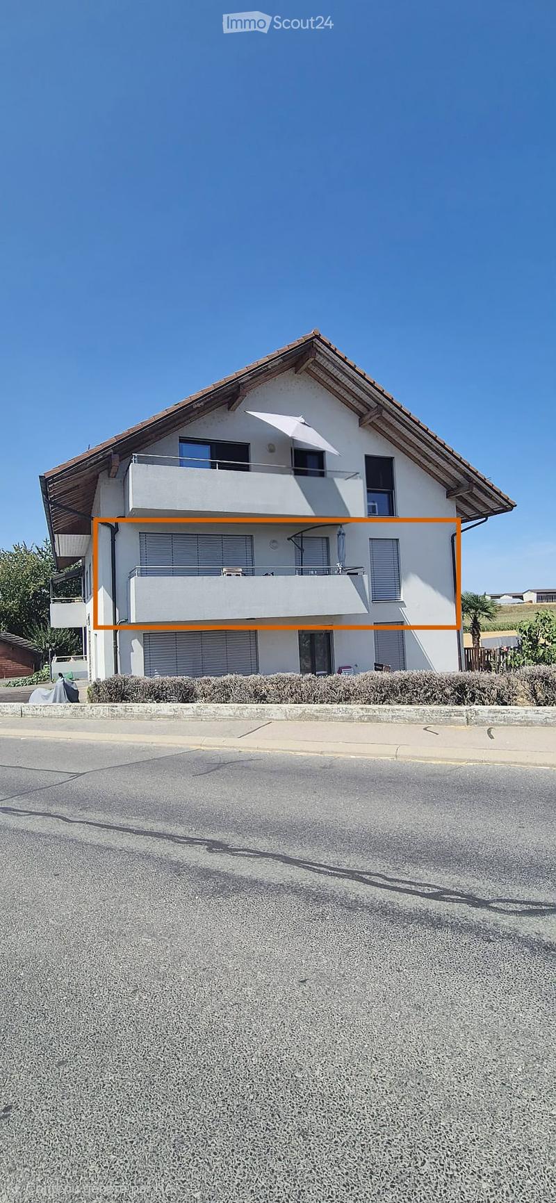 Two-story house with white exterior, multiple windows, balconies, and a covered patio area.