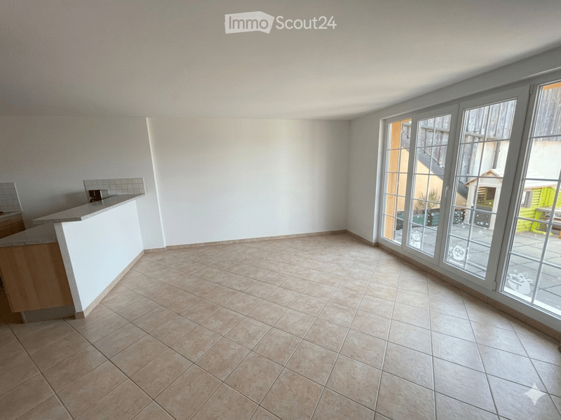Empty room with tiled floor, white walls, and large glass sliding doors leading to an outdoor area.