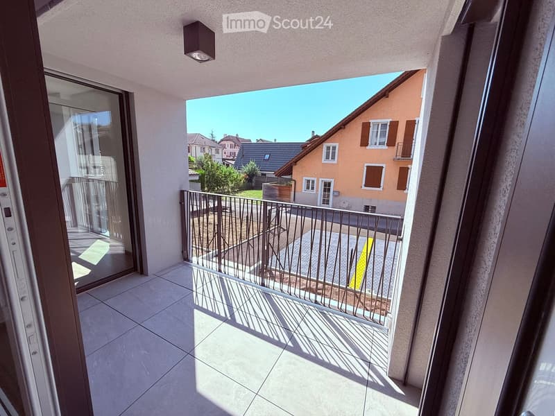 Balcony with tiled floor, metal railing, and a view of neighboring houses and greenery.
