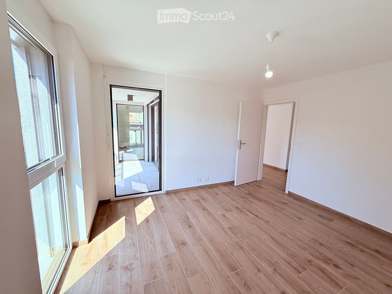 Empty room with wooden flooring, white walls, and large windows. No furniture or equipment present.