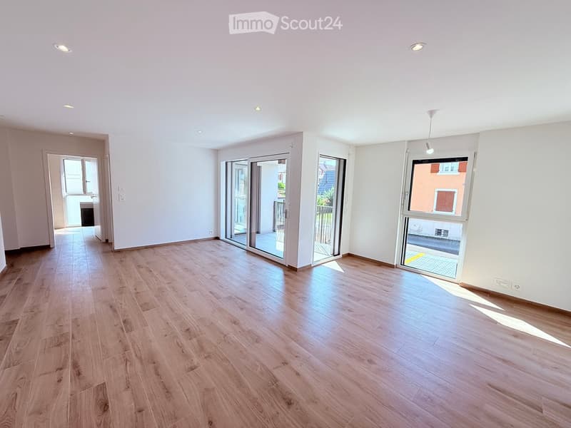 Empty room with wooden flooring, white walls, and large sliding glass doors leading to a balcony area.