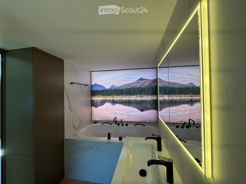 Modern bathroom with a large bathtub, double sink, and a scenic mural of a lake and mountains on the wall.