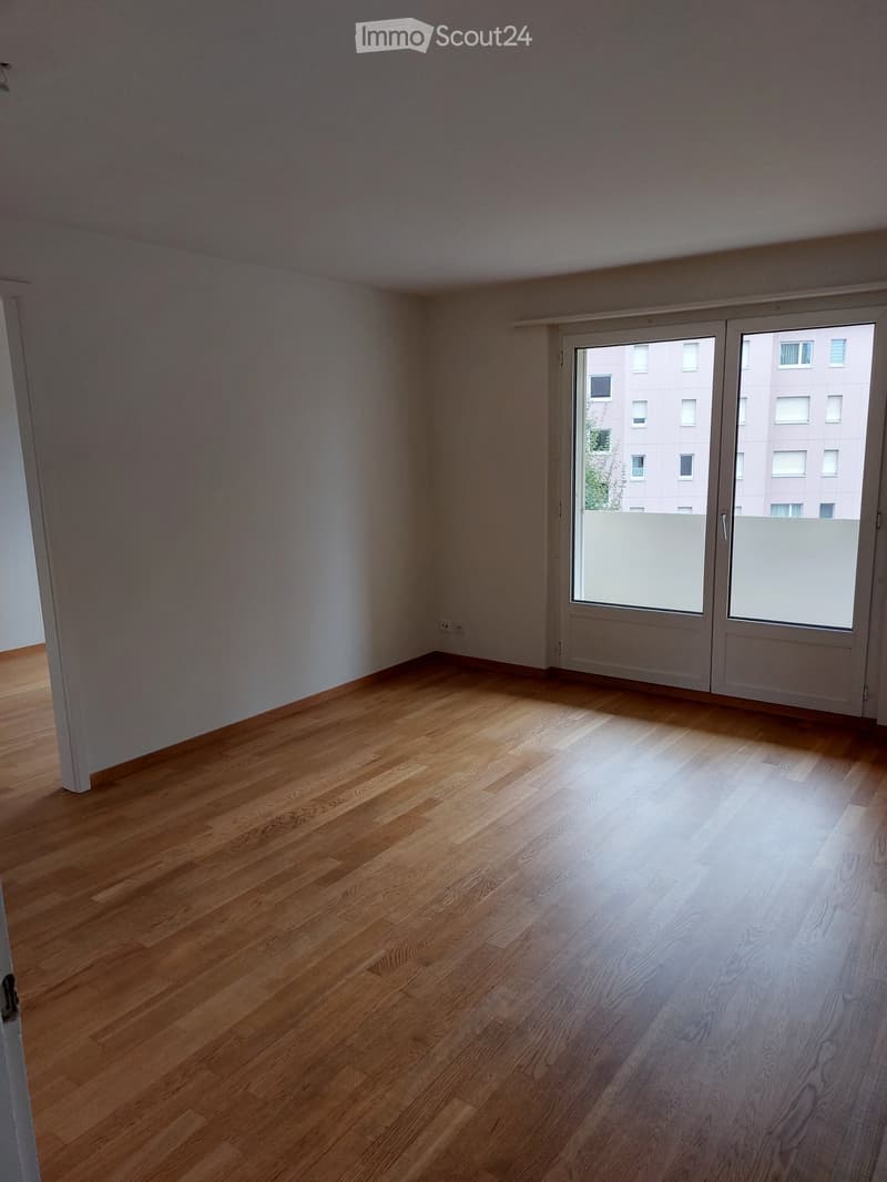 Empty room with wooden flooring and large sliding glass doors leading to a balcony or outdoor area.