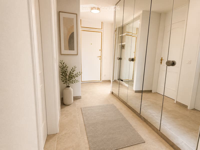 Modern hallway with tiled flooring, white walls, large mirror, framed artwork, and a small plant in a vase.