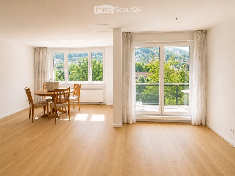 Bright dining area with wooden flooring, large windows offering scenic views, and a dining table with chairs.