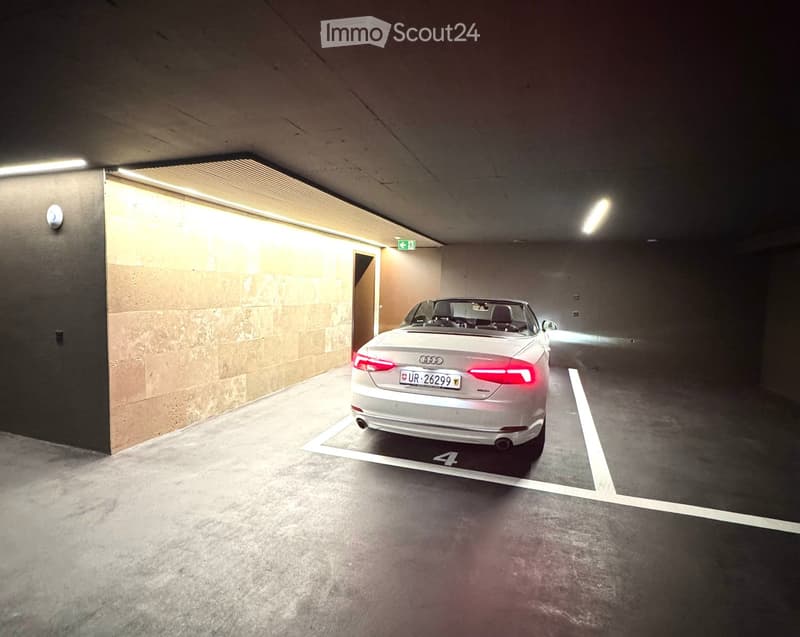 Other. Underground parking space with a single car parked in a designated spot, marked with the number 4. The area is well-lit with fluorescent lighting and features a clean, concrete floor and walls.