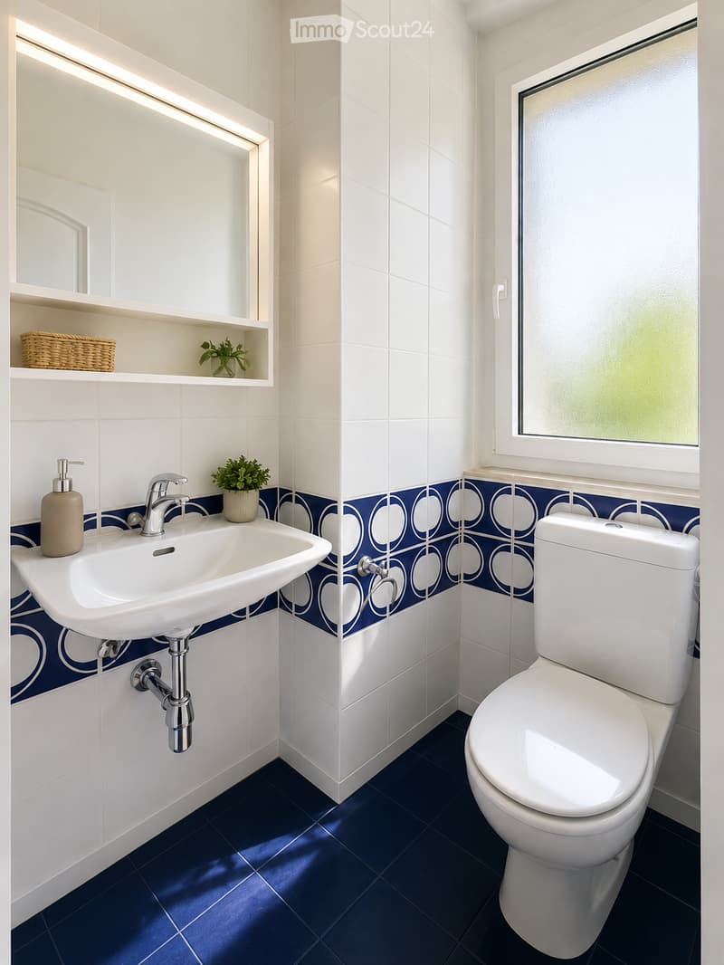 Modern bathroom with white tiles, blue accent tiles, a white sink, a chrome faucet, a white toilet, a large mirror, a shelf with a potted plant and a woven basket, and a soap dispenser.