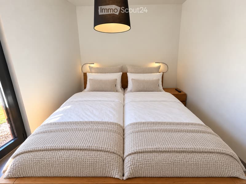 Modern bedroom with two single beds, beige bedding, nightstand, and pendant light.