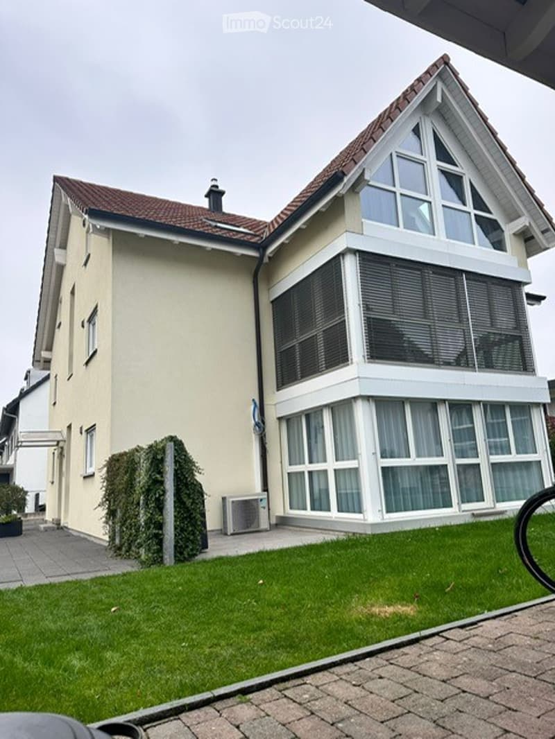 2 story house, beige exterior, large glass windows, brown roof, air conditioning unit, driveway, brick sidewalk