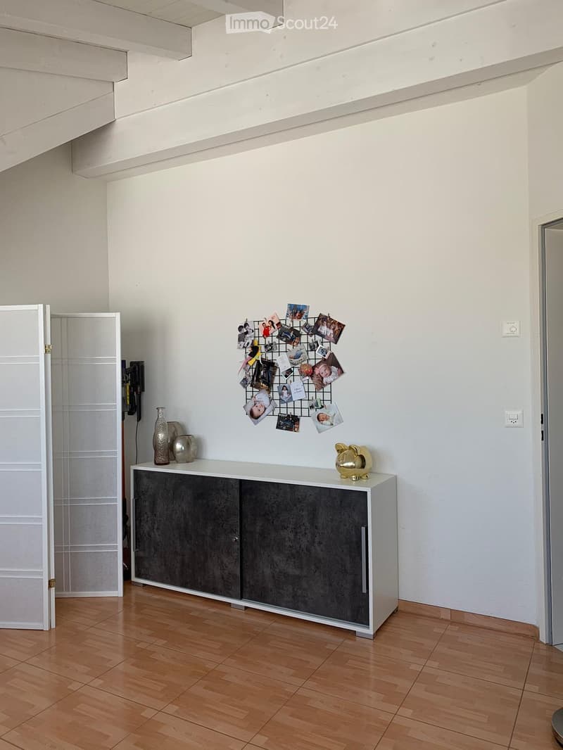 white walls, wooden floor, white cabinet with decorative objects on top