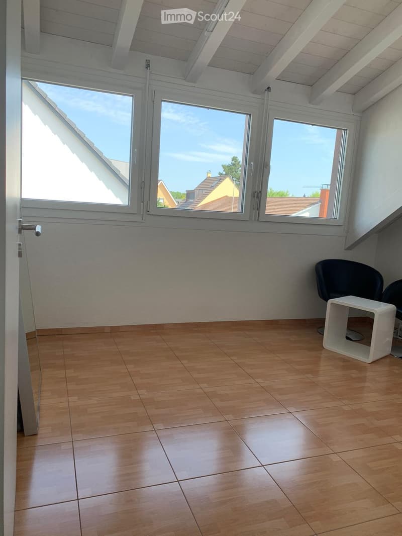 Empty room with wooden floor, large windows, and bright natural light.