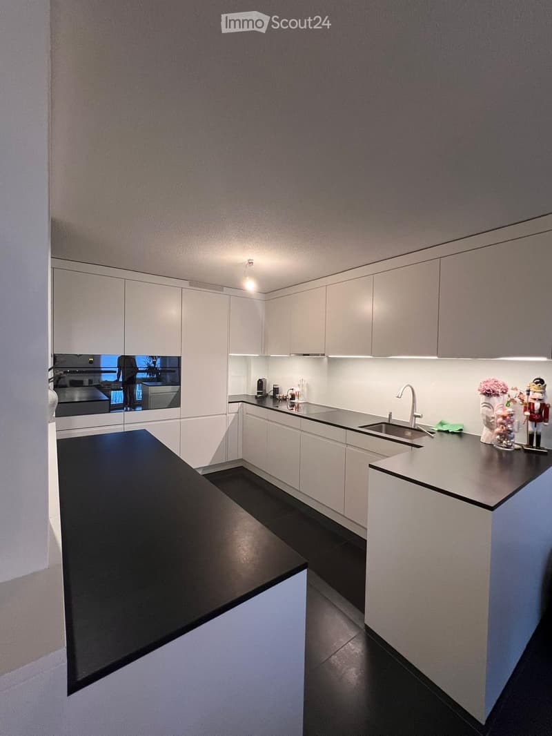 kitchen with white cabinets, black countertops, silver modern appliances, bright lighting
