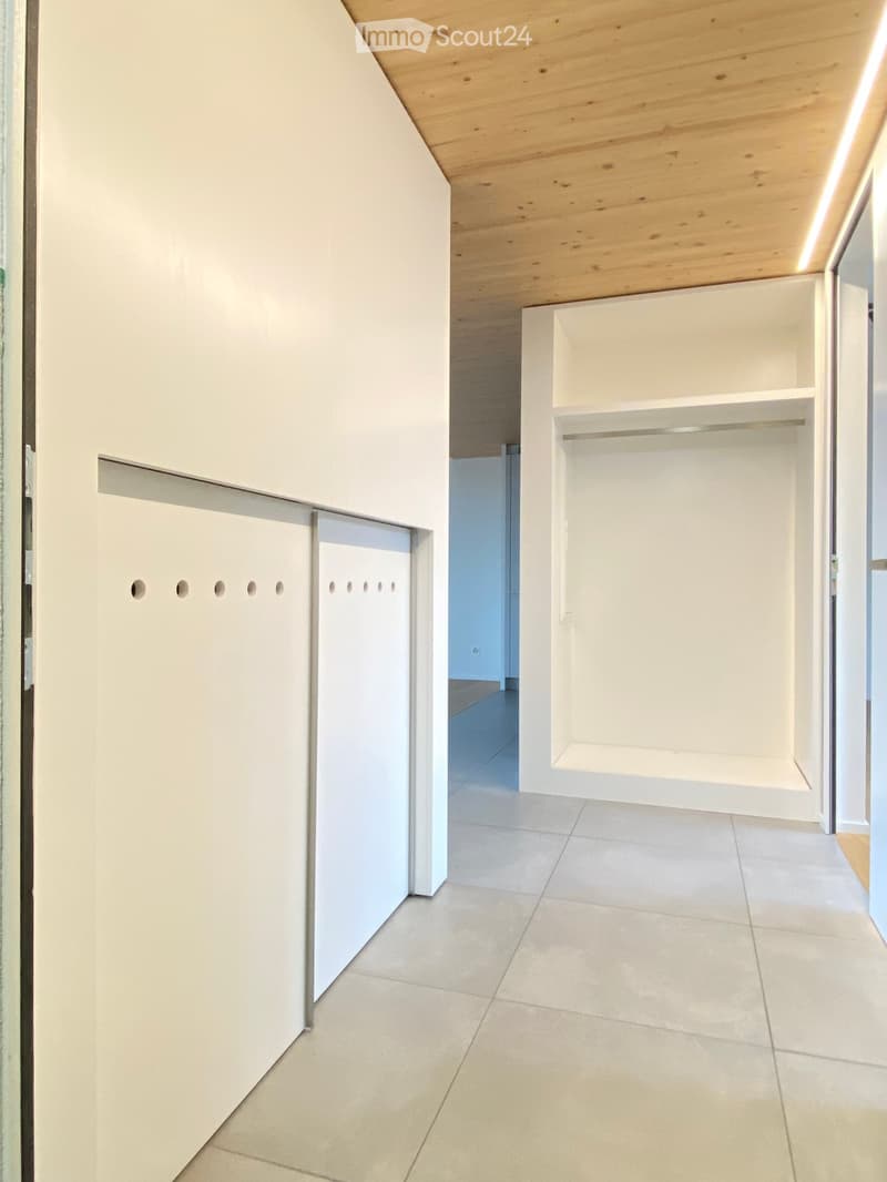Modern hallway with white walls, tiled floor, built-in storage units, and recessed lighting.